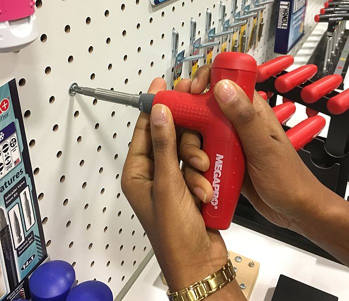 A T-handle Wrench driving a screw into a pegboard wall.